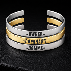 Silver and gold BDSM cuff bracelets engraved with Owner, Dominant and Domme, adjustable 8mm stainless steel power exchange jewellery from FETBOMB.