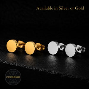 Gold and silver round earrings on a dark surface with 'FETBOMB' branding.