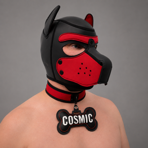 A person wearing a black and red dog-style hood mask with a red collar and a bone-shaped tag reading 'COSMIC' against a plain gray background.
