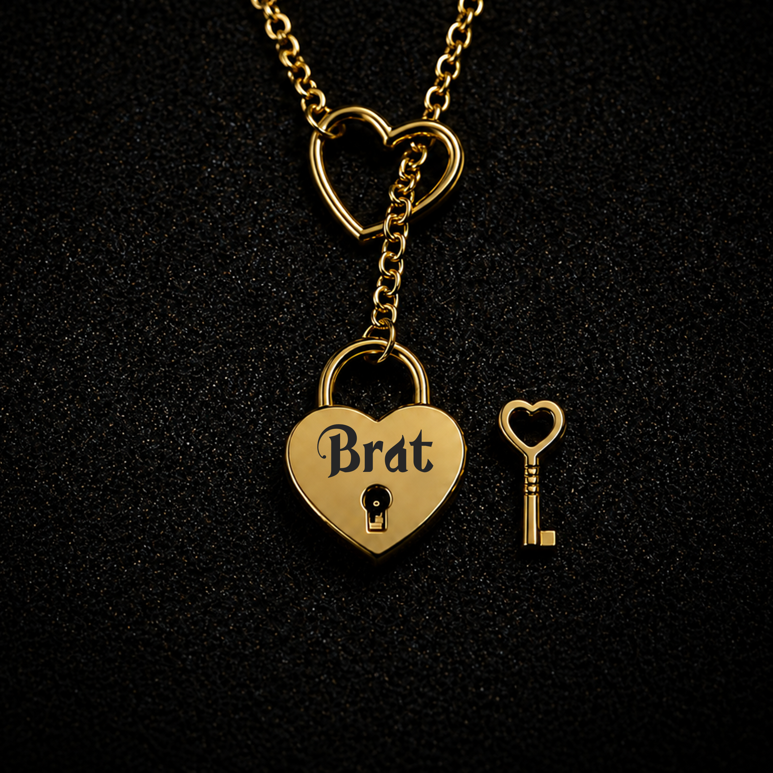 Gold heart-shaped pendant necklace with a lock and key design, featuring the word 'Brat' on the padlock, displayed on a textured black background.
