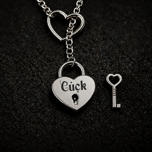 A silver heart-shaped padlock pendant engraved with the word 'Cuck' and a small matching heart-shaped key, displayed on a dark textured background.