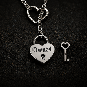 A silver heart-shaped padlock pendant engraved with the word 'Owned' and a small heart-shaped key, displayed on a dark textured background.