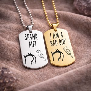 Spank Me and I Am a Bad Boy engraved BDSM dog tag necklaces in silver and gold stainless steel on fabric background