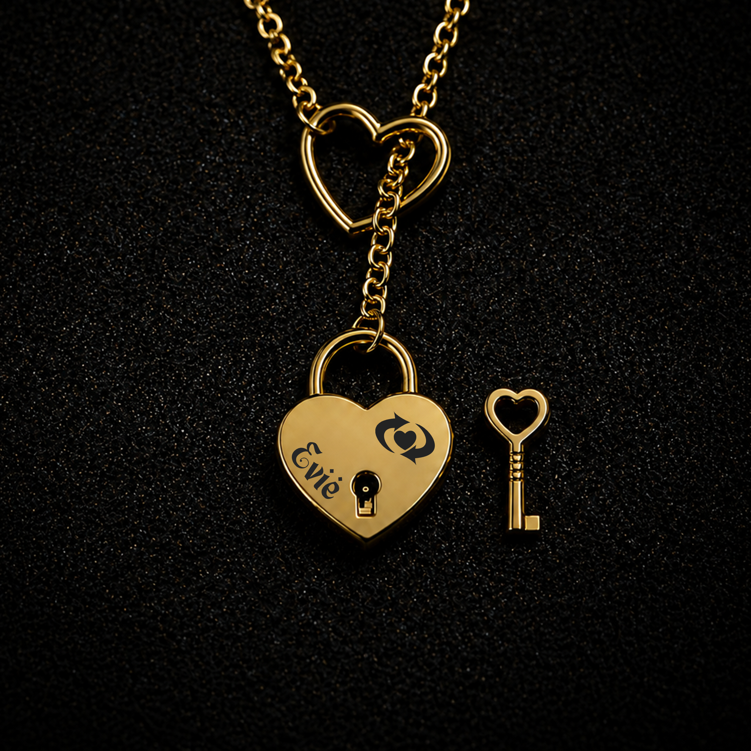 A gold heart-shaped pendant lock on a matching heart chain, shown with a small heart-shaped key on a textured black background. The lock is engraved with the name 'Evvie' and a heart with a keyhole inside.