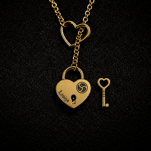 A gold heart-shaped lock pendant necklace on a black textured background, shown with a matching heart key and an open heart-shaped link charm at the top.